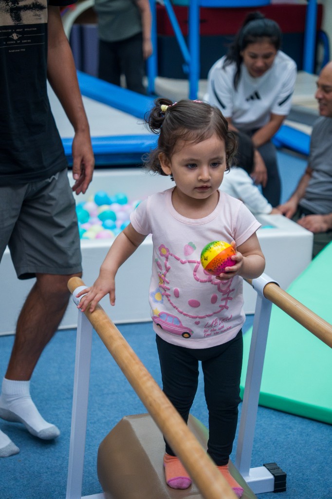 Niña en barras paralelas con pelota